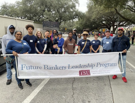 People holding a parade banner showing Allegiance Bank supports Future Bankers Leadership Program