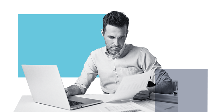 A man looking over documents about business fraud protection at his laptop