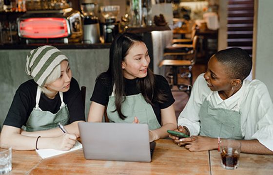 Three baristas discussing their finances at a table