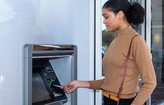 A woman entering her Stellar debit card at an ATM