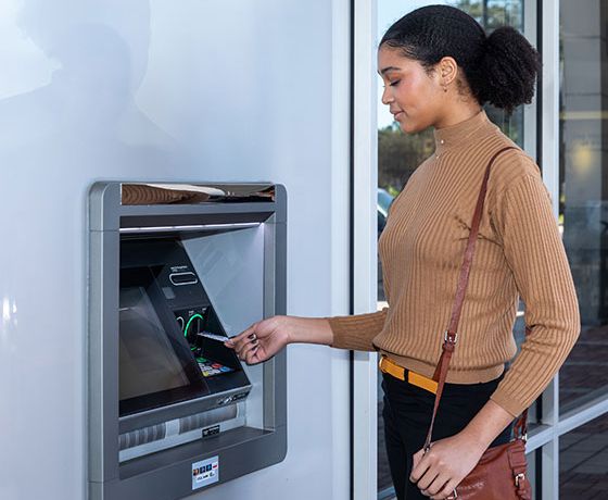 A woman entering her Stellar debit card at an ATM