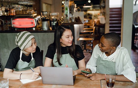Three baristas discussing their finances at a table