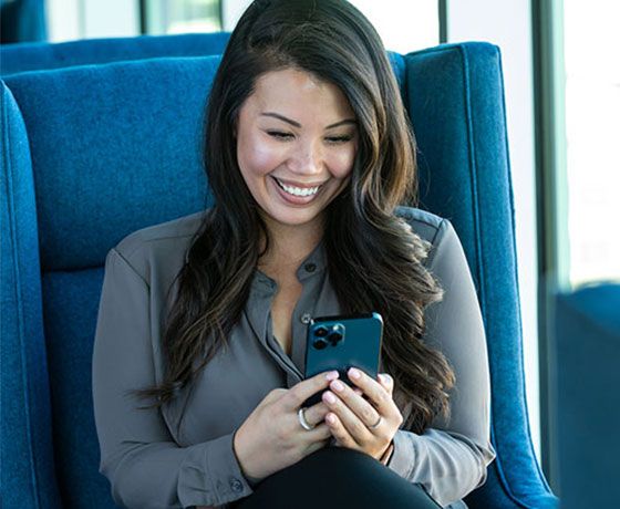A woman smiling while looking at the Stellar Bank Mobile App on her phone