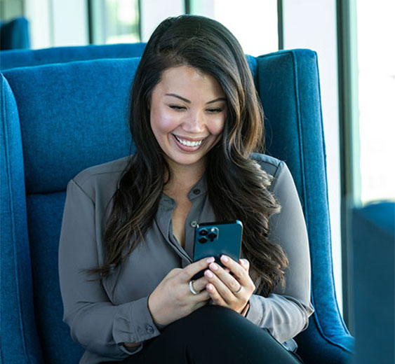A woman smiling while looking at the Stellar Bank Mobile App on her phone