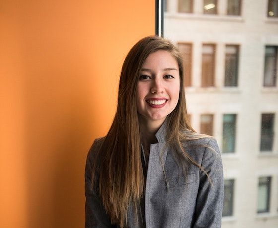 A female Stellar employee smiling by an orange wall