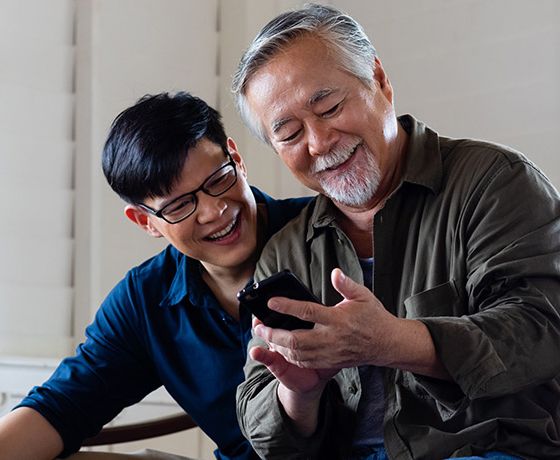 An Asian father and son exploring mobile banking with the Stellar on an iphone