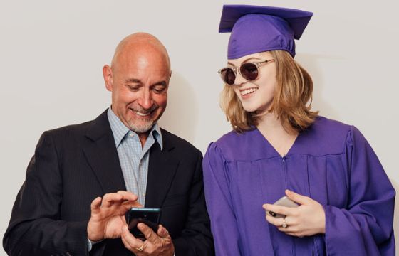 A man using Zelle on his phone to send money to a woman graduating