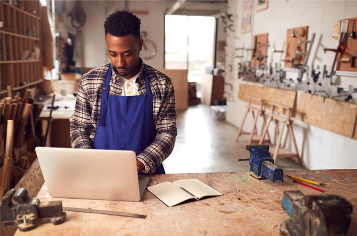 A man looking at his laptop in a woodshop