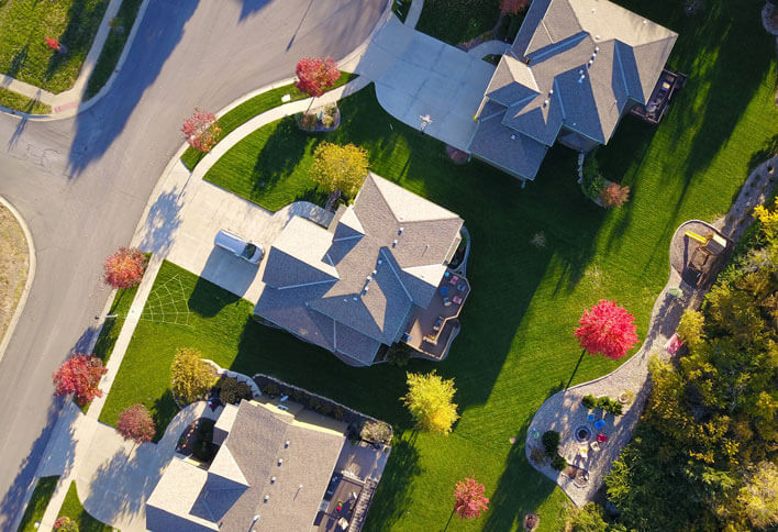 An aerial view of a two story house in a neighborhood at sunset