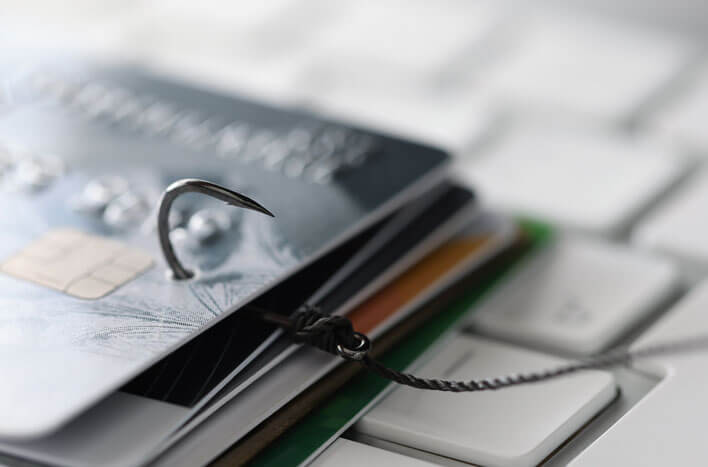 A fishing hook piercing a stack of credit cards