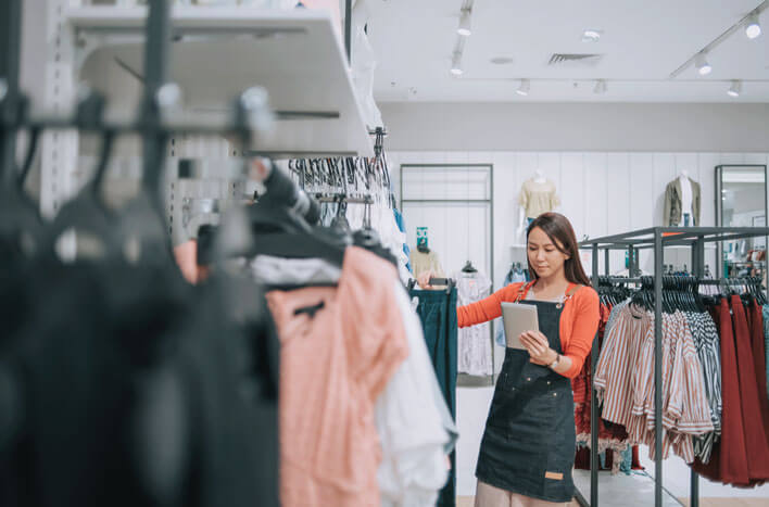 A clerk in a clothing store making notes about inventory